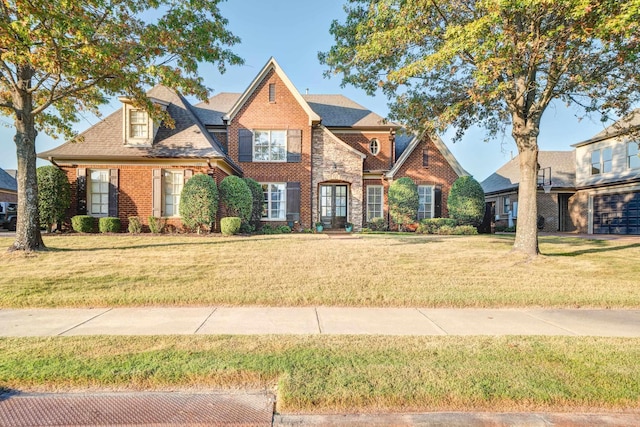 view of front of home featuring a front lawn, roof with shingles, and brick siding