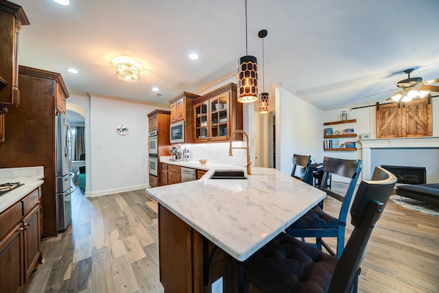 kitchen with arched walkways, glass insert cabinets, appliances with stainless steel finishes, ornamental molding, and a kitchen bar