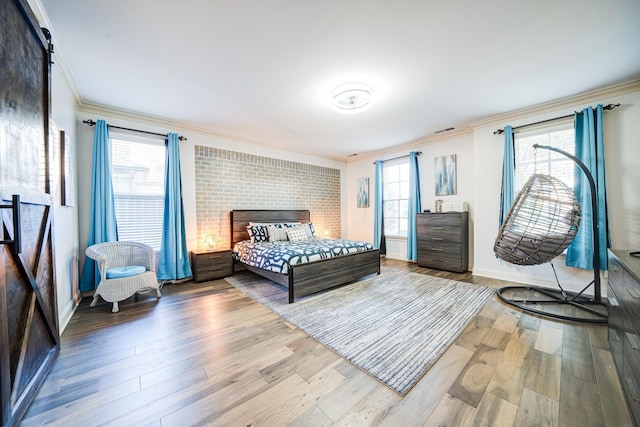 bedroom with baseboards, visible vents, crown molding, and wood finished floors