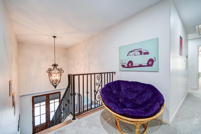 sitting room with baseboards, carpet floors, an upstairs landing, and a notable chandelier