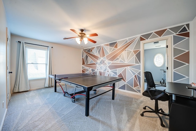 playroom with carpet floors, ceiling fan, an accent wall, and baseboards