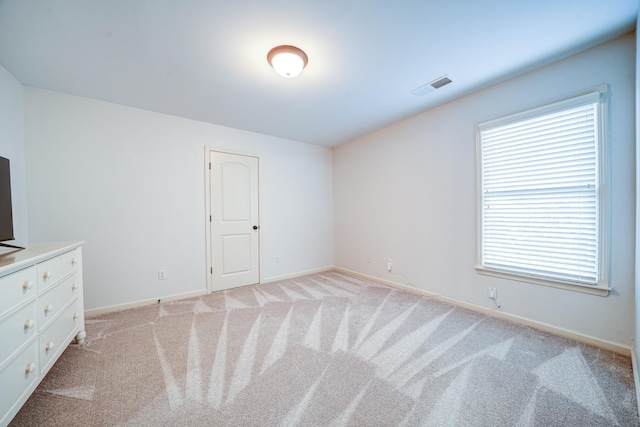 unfurnished bedroom featuring visible vents, light carpet, and baseboards