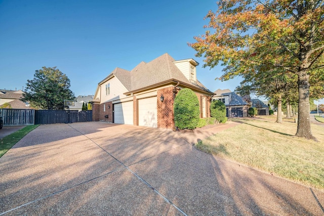 view of property exterior with a garage, a lawn, concrete driveway, fence, and brick siding