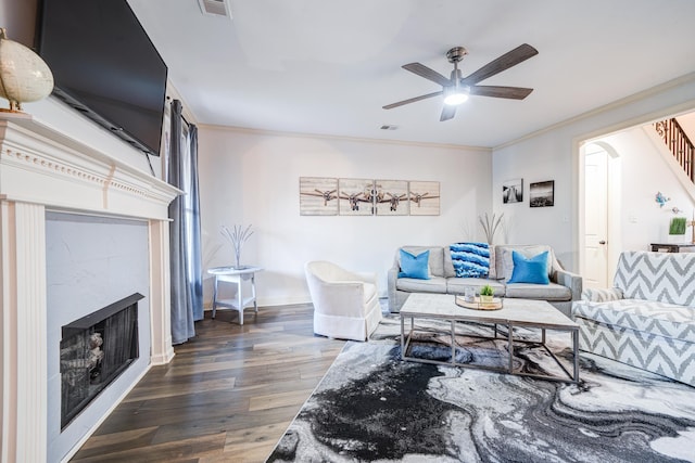 living area with ornamental molding, a premium fireplace, wood finished floors, and visible vents