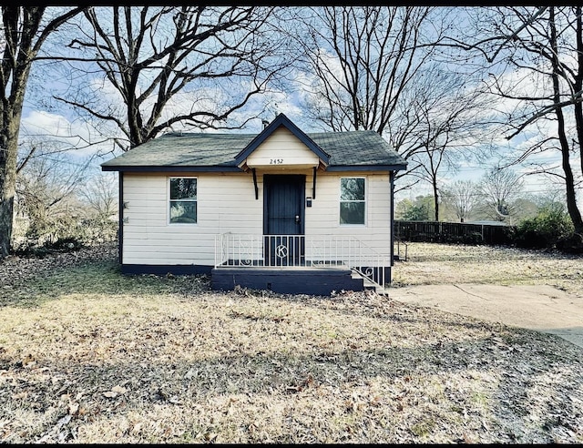 view of front of property featuring a shingled roof and fence