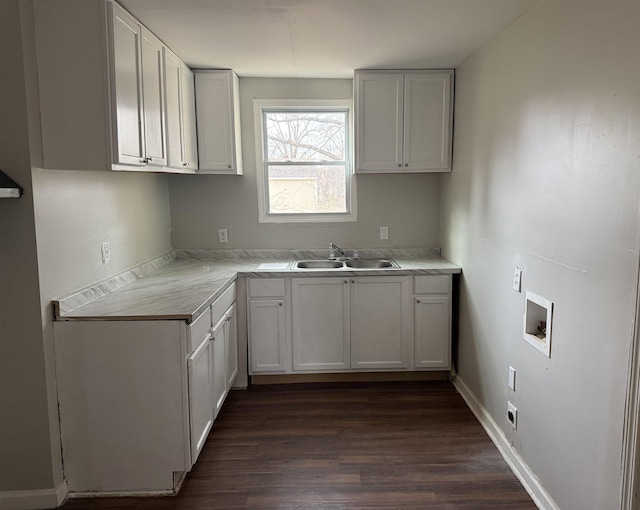 kitchen featuring light countertops, dark wood-style flooring, a sink, and white cabinetry