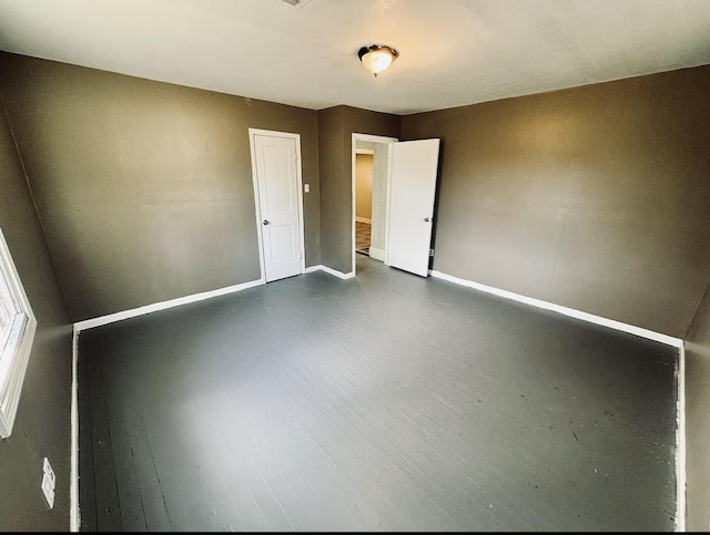 unfurnished room with dark wood-style flooring and baseboards