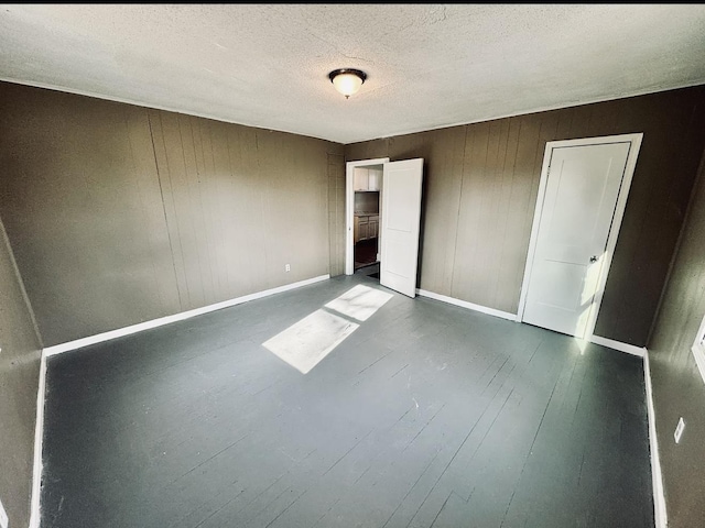 unfurnished bedroom with baseboards, dark wood finished floors, and a textured ceiling