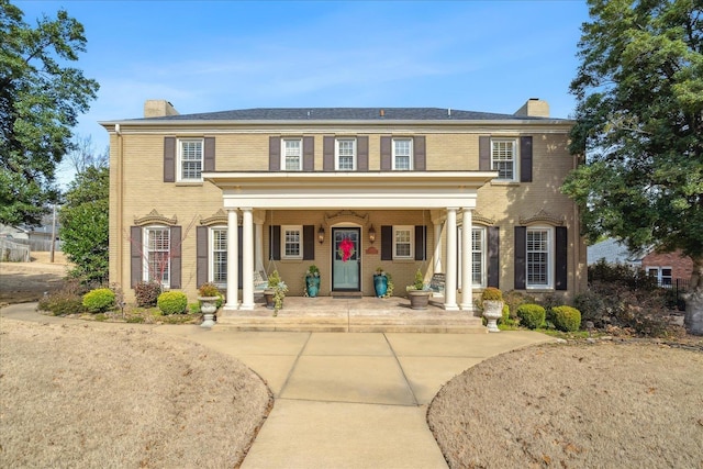 view of front of property with brick siding, a chimney, and a porch