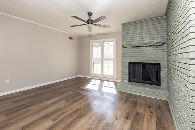 unfurnished living room with visible vents, baseboards, wood finished floors, crown molding, and a brick fireplace