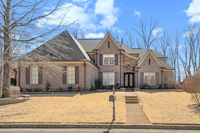 french provincial home with french doors, brick siding, and a shingled roof