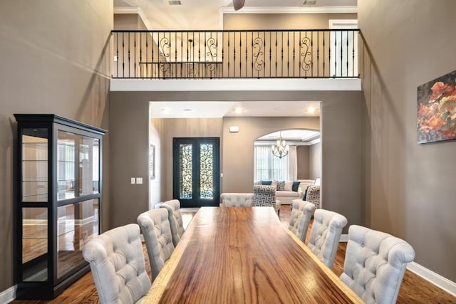 dining room with french doors, a high ceiling, an inviting chandelier, wood finished floors, and baseboards