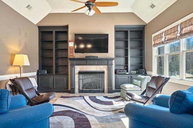 living room featuring lofted ceiling, ceiling fan, a tile fireplace, and visible vents