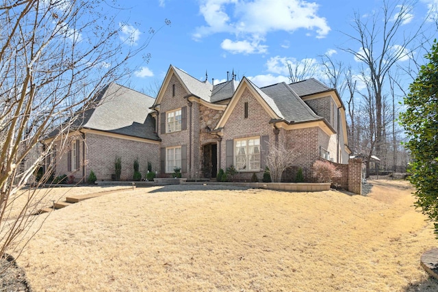 view of front of home featuring roof with shingles and brick siding