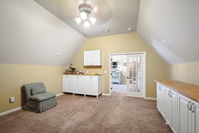 sitting room with baseboards, visible vents, vaulted ceiling, and light colored carpet