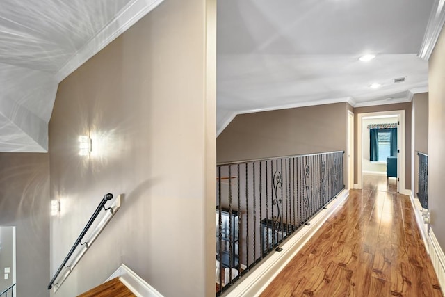 corridor featuring ornamental molding, baseboards, an upstairs landing, and wood finished floors