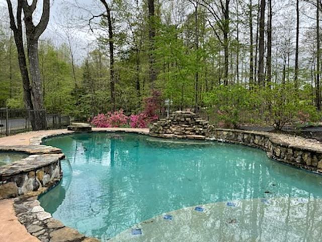 view of pool with a pool with connected hot tub and fence