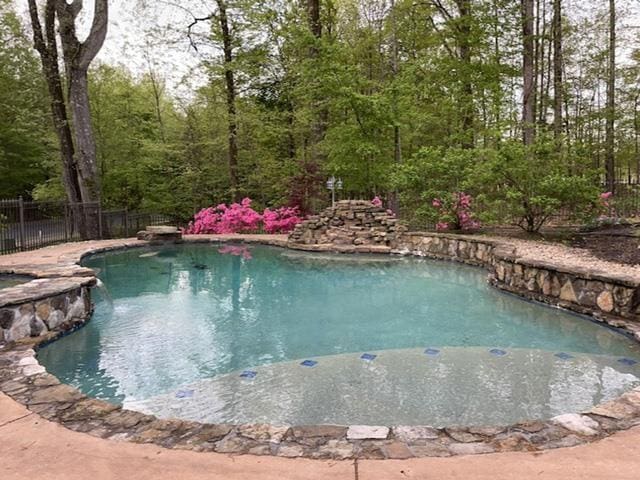 view of swimming pool with a pool with connected hot tub and fence