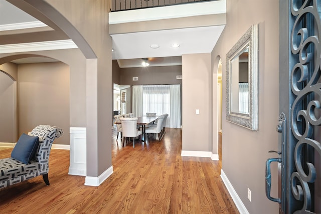 foyer entrance featuring light wood-type flooring, arched walkways, and baseboards