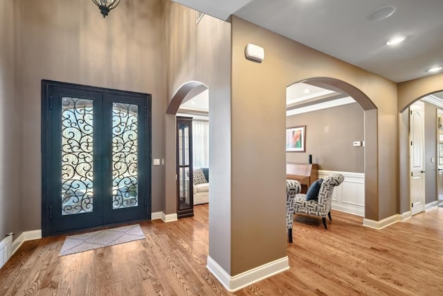 foyer entrance with arched walkways, crown molding, wood finished floors, and baseboards