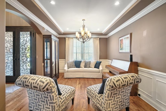 sitting room with a chandelier, arched walkways, french doors, and wainscoting