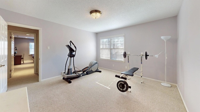 exercise room with a healthy amount of sunlight, a textured ceiling, and baseboards