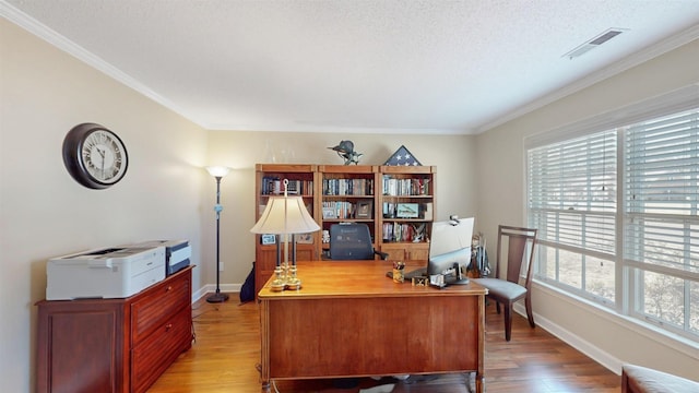 office with ornamental molding, light wood-type flooring, visible vents, and baseboards