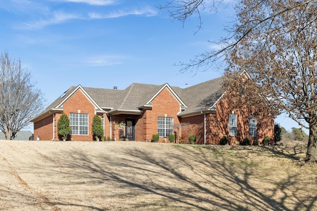 view of front of property featuring brick siding and a shingled roof