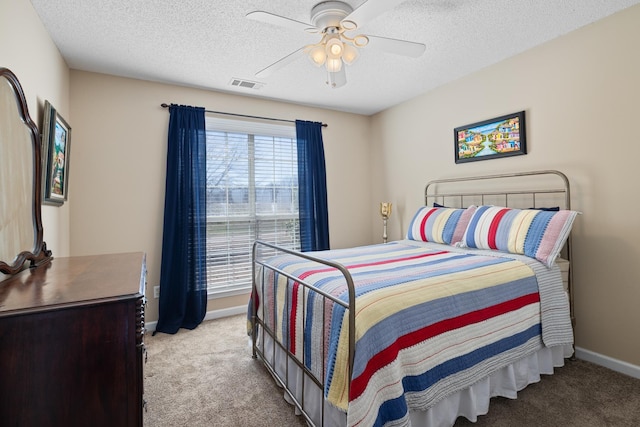 carpeted bedroom featuring a ceiling fan, visible vents, a textured ceiling, and baseboards