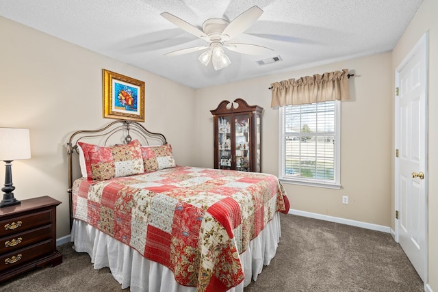 bedroom with a textured ceiling, dark colored carpet, visible vents, and baseboards