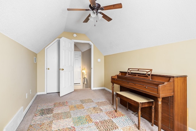 sitting room with vaulted ceiling, a textured ceiling, baseboards, and light colored carpet