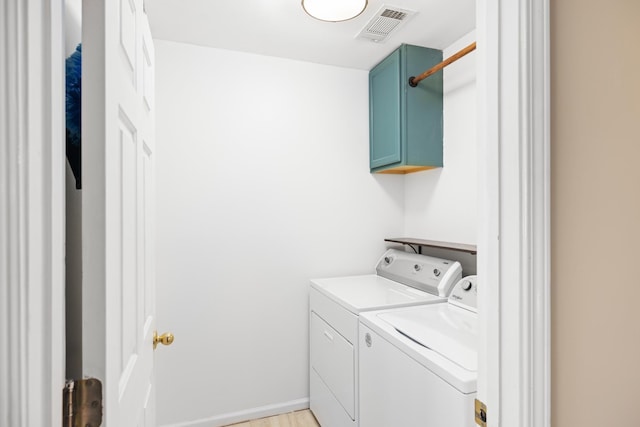 clothes washing area featuring cabinet space, visible vents, and washer and dryer