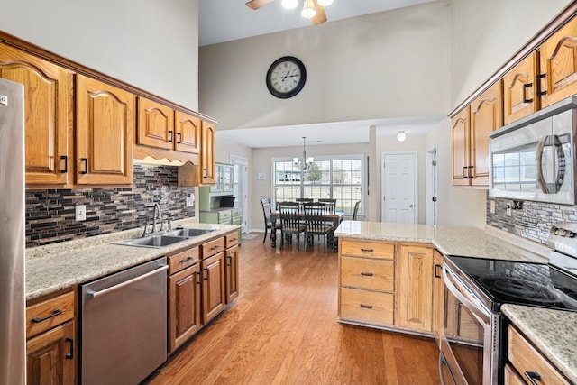 kitchen with stainless steel appliances, light countertops, a sink, and a high ceiling