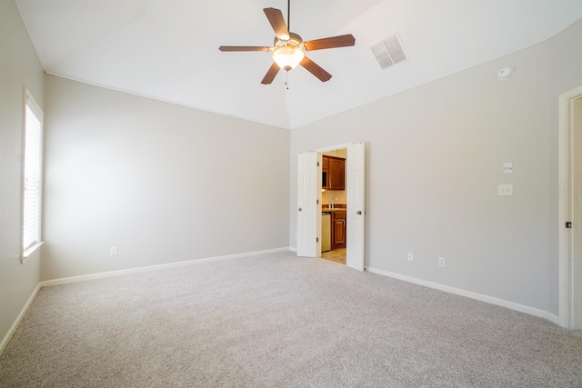 spare room with light carpet, baseboards, visible vents, a ceiling fan, and lofted ceiling