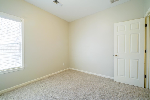 carpeted spare room with visible vents and baseboards