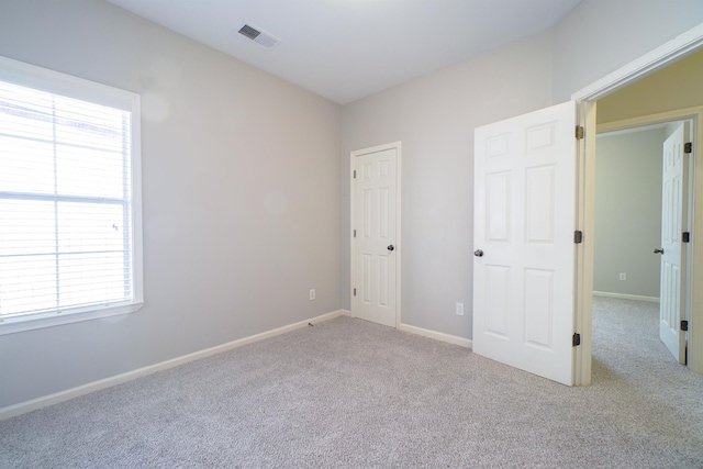 unfurnished bedroom featuring carpet, visible vents, and baseboards