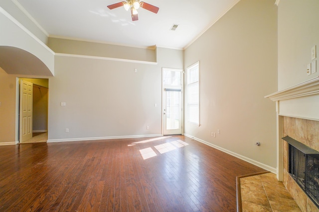 unfurnished living room with crown molding, wood finished floors, a tile fireplace, and baseboards