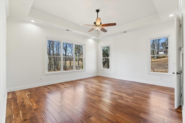 unfurnished room featuring baseboards, a raised ceiling, wood finished floors, and ornamental molding