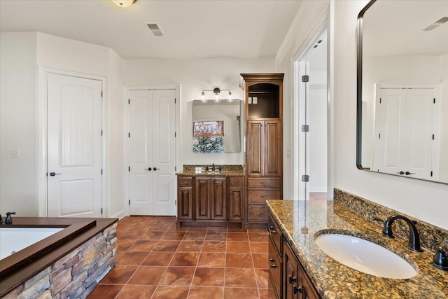 bathroom with visible vents, two vanities, and a sink