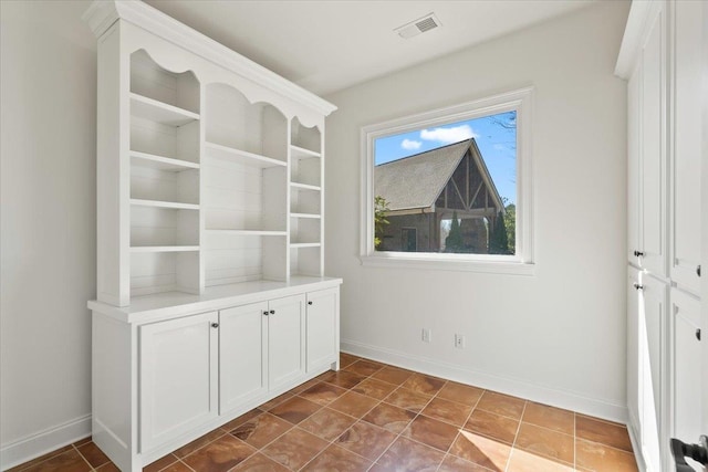 interior space featuring baseboards, visible vents, and dark tile patterned flooring