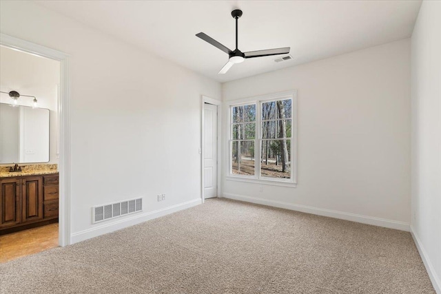 empty room with ceiling fan, a sink, visible vents, and light colored carpet