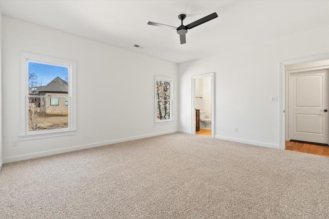 unfurnished bedroom featuring ensuite bathroom, carpet flooring, a ceiling fan, visible vents, and baseboards