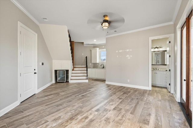 unfurnished living room featuring crown molding, light wood-style flooring, and baseboards