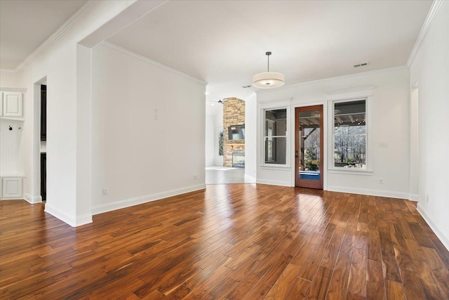 unfurnished room featuring wood-type flooring, ornamental molding, and a stone fireplace