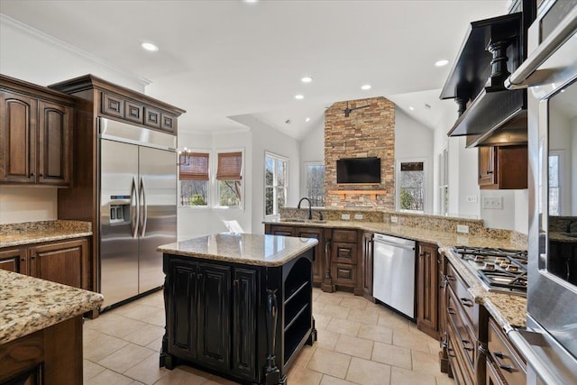 kitchen featuring a kitchen island, light stone countertops, vaulted ceiling, stainless steel appliances, and recessed lighting