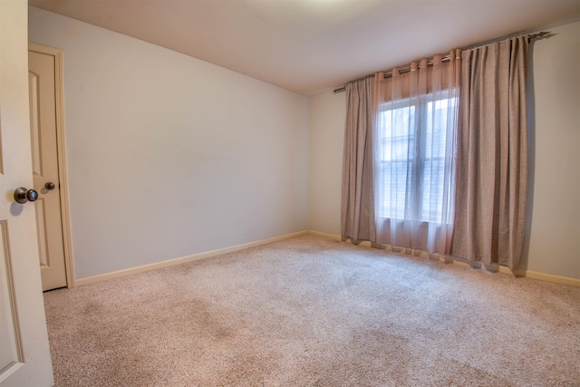 carpeted empty room featuring baseboards