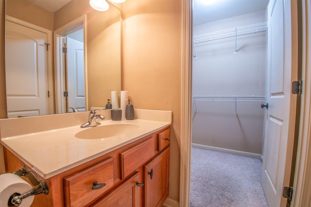 bathroom with a walk in closet and vanity