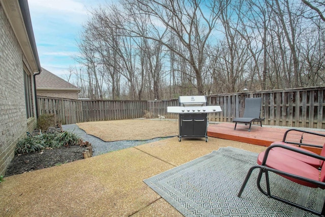 view of patio with a deck, a fenced backyard, and a grill