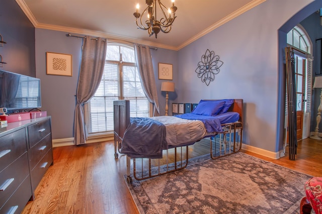 bedroom with ornamental molding, arched walkways, and wood finished floors