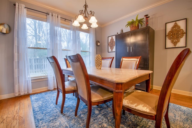 dining room featuring a wealth of natural light, crown molding, baseboards, and wood finished floors